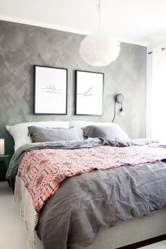 a bedroom with grey walls and two pictures on the wall above the bed, along with candles