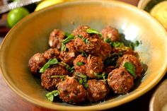 a bowl filled with meatballs and garnish on top of a wooden table