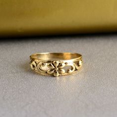 a gold ring with an ornate design on the outside and inside, sitting on a table