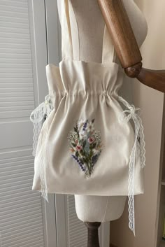 a white bag with flowers on it sitting on top of a mannequin