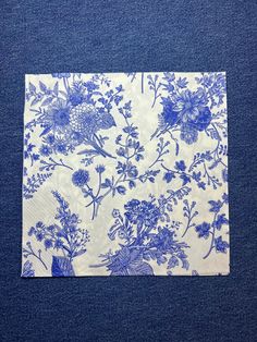 a blue and white flowered napkin on a blue surface with an image of flowers in the background