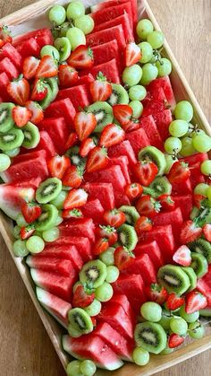 watermelon, kiwi and grapes arranged on a platter for a party