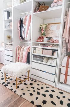 a white closet filled with lots of clothes and shoes next to a black and white rug