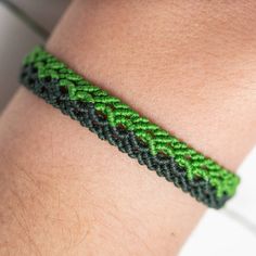 a close up of a person's arm wearing a green and black braided bracelet