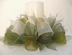 a white candle is sitting next to some green organes and mesh ribbons on a table