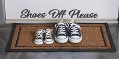 three pairs of sneakers are sitting on a mat in front of a sign that says shoes off please