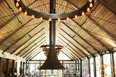 a large open room with many tables and lights on the ceiling is lit by lamps that are hanging from the rafters