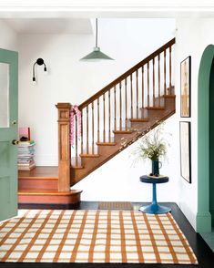 a room with a rug, table and stairs in front of the door to another room