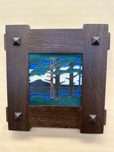 a wooden frame with stained glass in the shape of trees and mountains, on a beige background