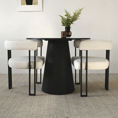 a black table with four white chairs and a potted plant sitting on top of it