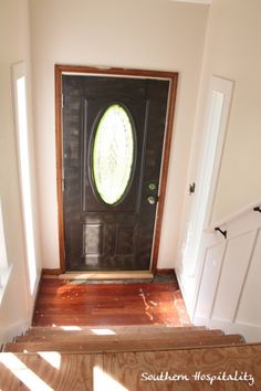 an entryway with a black door and wooden steps