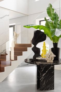 a plant in a black vase sitting on top of a table next to some stairs