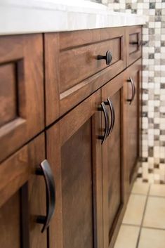 a bathroom with wooden cabinets and tile flooring on the walls, along with white counter tops