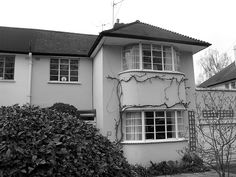 a black and white photo of a house with vines growing on it's side