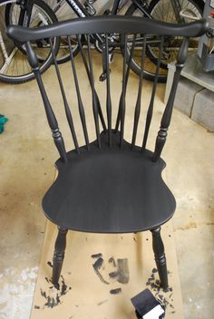 a black chair sitting on top of a piece of wood next to a pair of bicycles