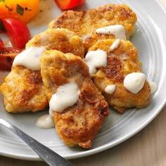 some food is sitting on a white plate with a knife and fork next to it