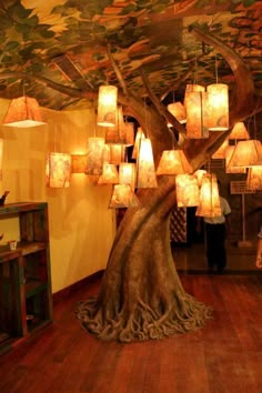 a large tree with many lamps hanging from it's branches in the middle of a room