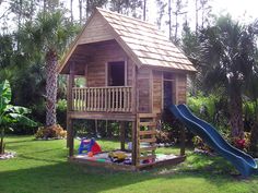 a small wooden house with a slide in the yard