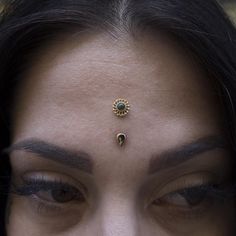 a close up of a woman's face with a nose ring on her forehead