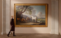 a woman walking past a painting with horses