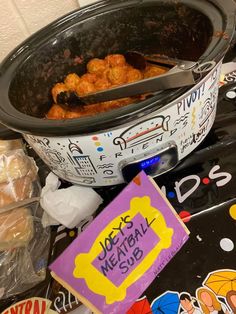 a crock pot filled with meatballs next to some candy bar wrappers and stickers