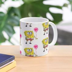 a coffee mug with cartoon characters on it sitting on a table next to some books