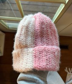 a pink and white knitted hat sitting on top of a table