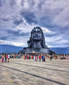 many people are standing around a large statue