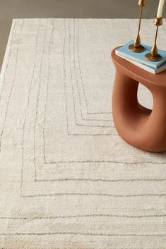 a table with two candles on top of it next to a rug in the middle