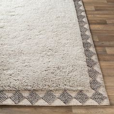 a white and gray rug on top of a wooden floor next to a hardwood floor