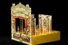 an elaborately designed display case with paintings on the front and sides, in gold