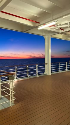 an empty deck overlooking the ocean at sunset with benches and railings on each side