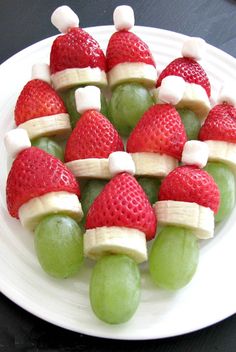 some fruit is arranged in the shape of santa's hats on a white plate