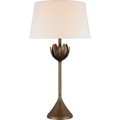 a table lamp with a white shade on the base and a gold metal flower design