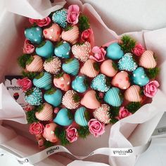 there are many heart shaped cupcakes in the box on the table with flowers