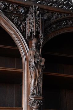 an ornate wooden sculpture on the side of a building with bookshelves behind it