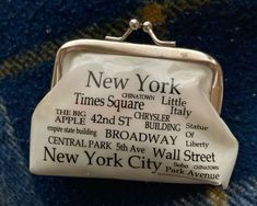 a small white purse sitting on top of a blue carpeted floor with the words new york printed on it