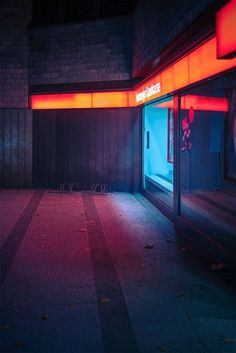 an empty room with red light coming from the windows and floor, in front of a brick wall