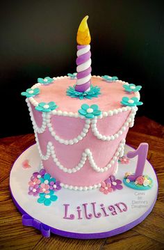 a pink and purple birthday cake with a candle on top that says lillian