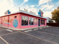 an empty parking lot in front of a pink building with the words top drawer painted on it