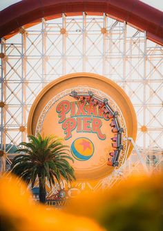 an amusement park sign with palm trees in the foreground and ferris wheel in the background