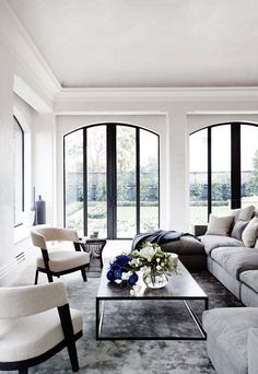 a living room filled with lots of furniture next to large open windows and french doors