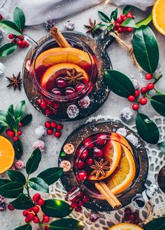 two glasses of mulled tea with orange slices and cranberries on the side