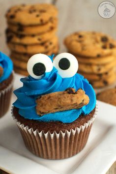 a cupcake with blue frosting and googly eyes sitting on top of a plate