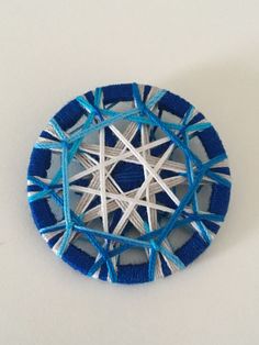 a blue and white brooch with an intricate design in the center on a white surface