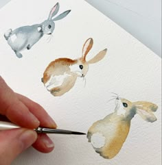 someone is painting three rabbits with watercolors