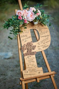 a wooden sign with flowers and greenery on it