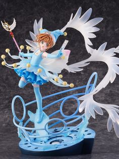 the figurine is holding a wand and wearing a blue dress with white wings