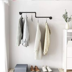 an organized closet with shoes, sweaters and other items hanging on the wall next to a shoe rack