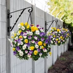 several hanging baskets filled with colorful flowers next to a wall